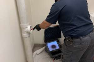 Technicain using sewer camera through clean out WEB